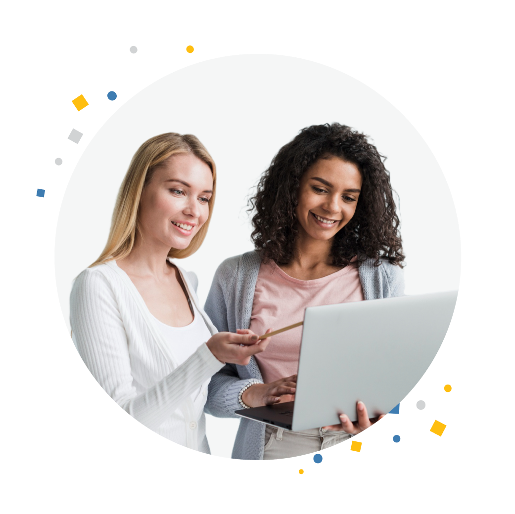 Two women, one holding a laptop and the other pointing at its screen.